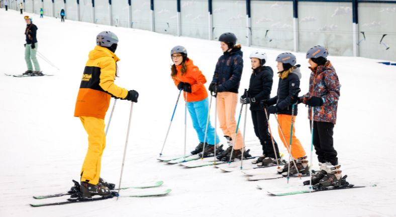 Leerlingen krijgen voor de eerste keer skiles van de skileraar.